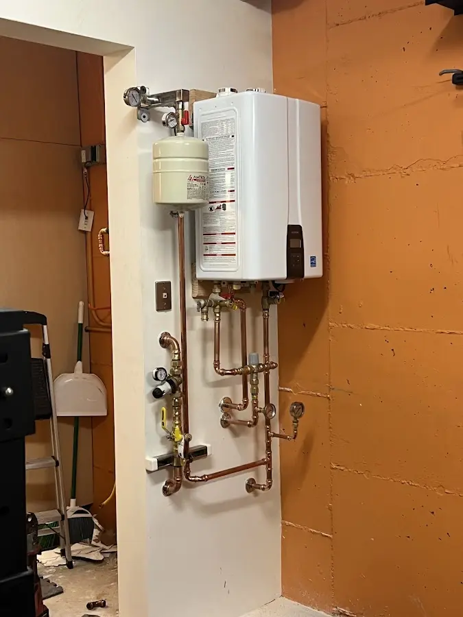 Plumbing technician inspecting water heater connections in Cranston